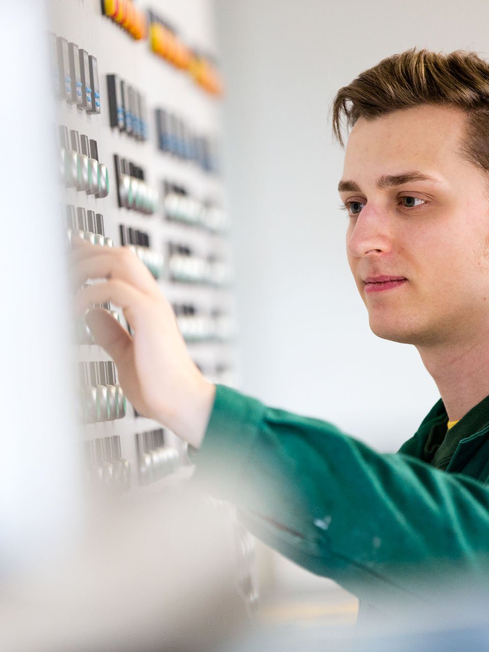 Ein Chemikant im grünen Overall überprüft Schaltknöpfe