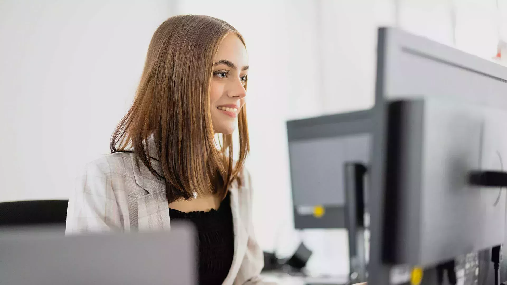 Industriekauffrau sitzt vor einem Computerbildschirm und arbeitet