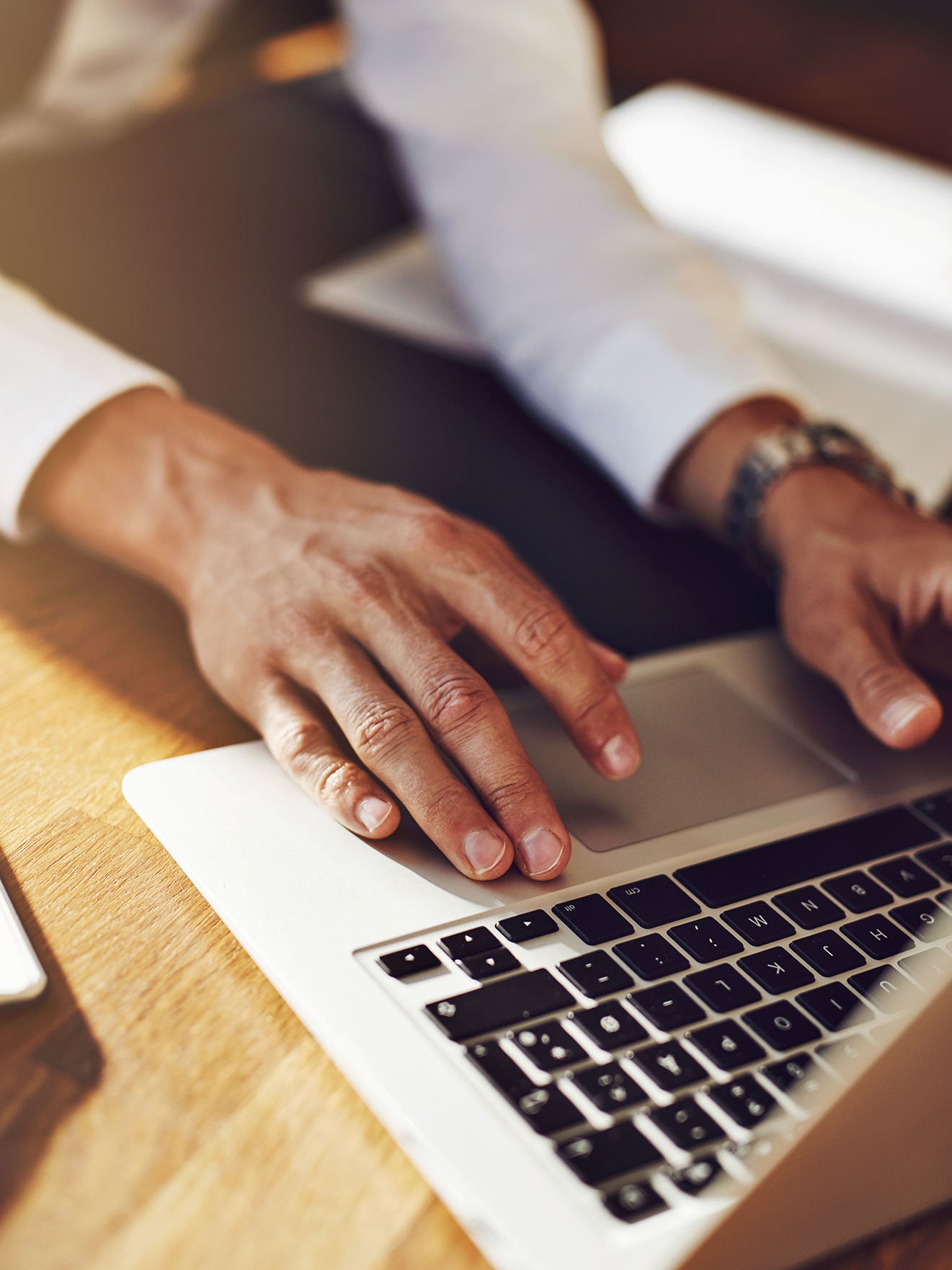 Eine Person sitzt vor dem Laptop und verwendet die Tastatur